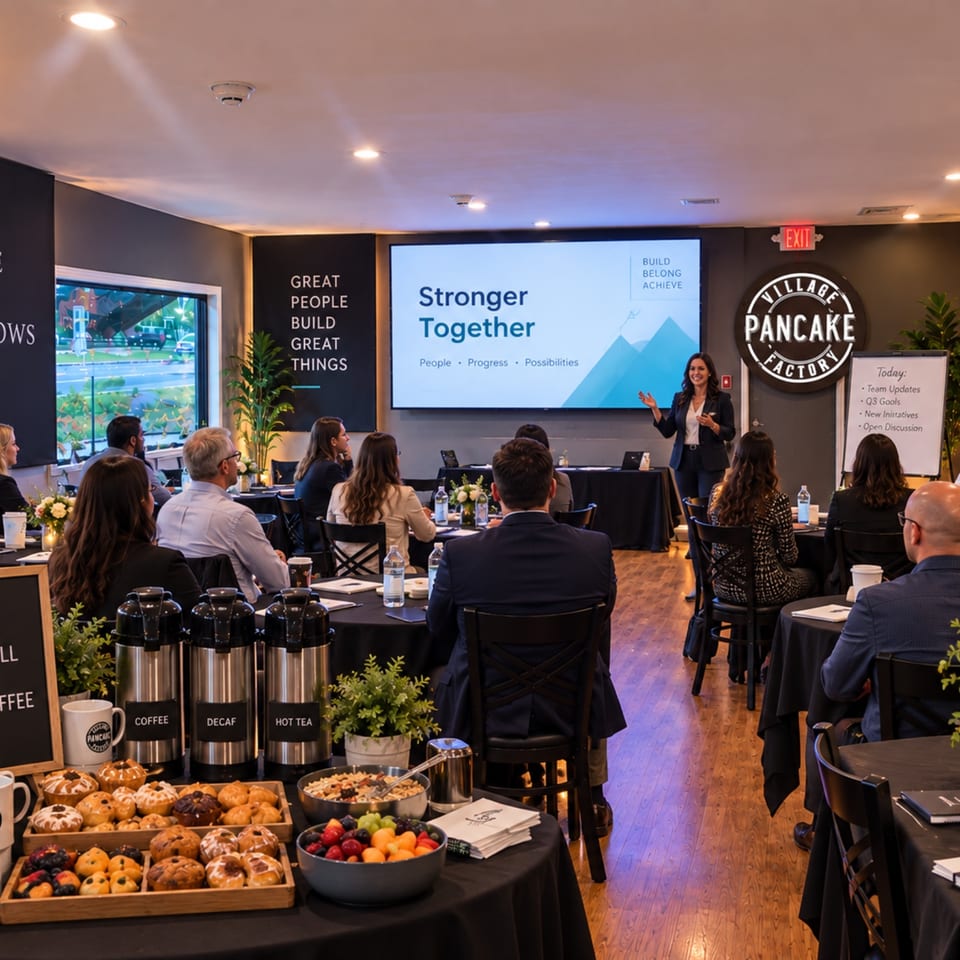 Pancake Factory conference room with a presenter addressing attendees, breakfast pastries, fruit, and coffee stations.